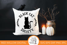 Load image into Gallery viewer, Black Cat Society SVG on a white throw pillow with halloween decor surrounding it.
